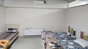 Une chambre avec deux lits, un radiateur et un appareil de climatisation fixé au mur.