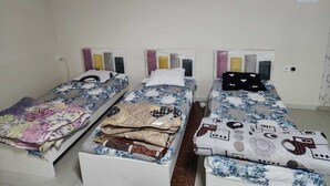 Une chambre avec trois lits simples, chacun recouvert d’une couvre-lit à motifs différents.