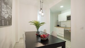 A dining area with a black table, a potted plant, and a hanging light fixture.