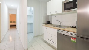 A modern kitchen with white cabinets, a stainless steel refrigerator, a microwave, and a sink.