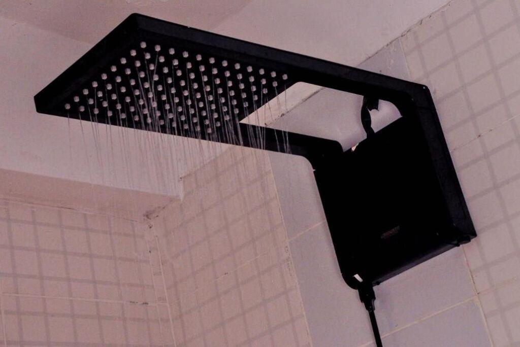 Un cabezal de ducha con múltiples boquillas, instalado en una pared con azulejos.