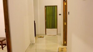 A hotel hallway with a wooden floor, a green curtain, and a welcome mat at the end. - Sesali Residences (Kandy)