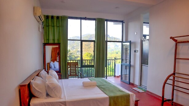 A hotel room with a bed, a chair, a balcony with a view, and a TV. - Sesali Residences (Kandy)