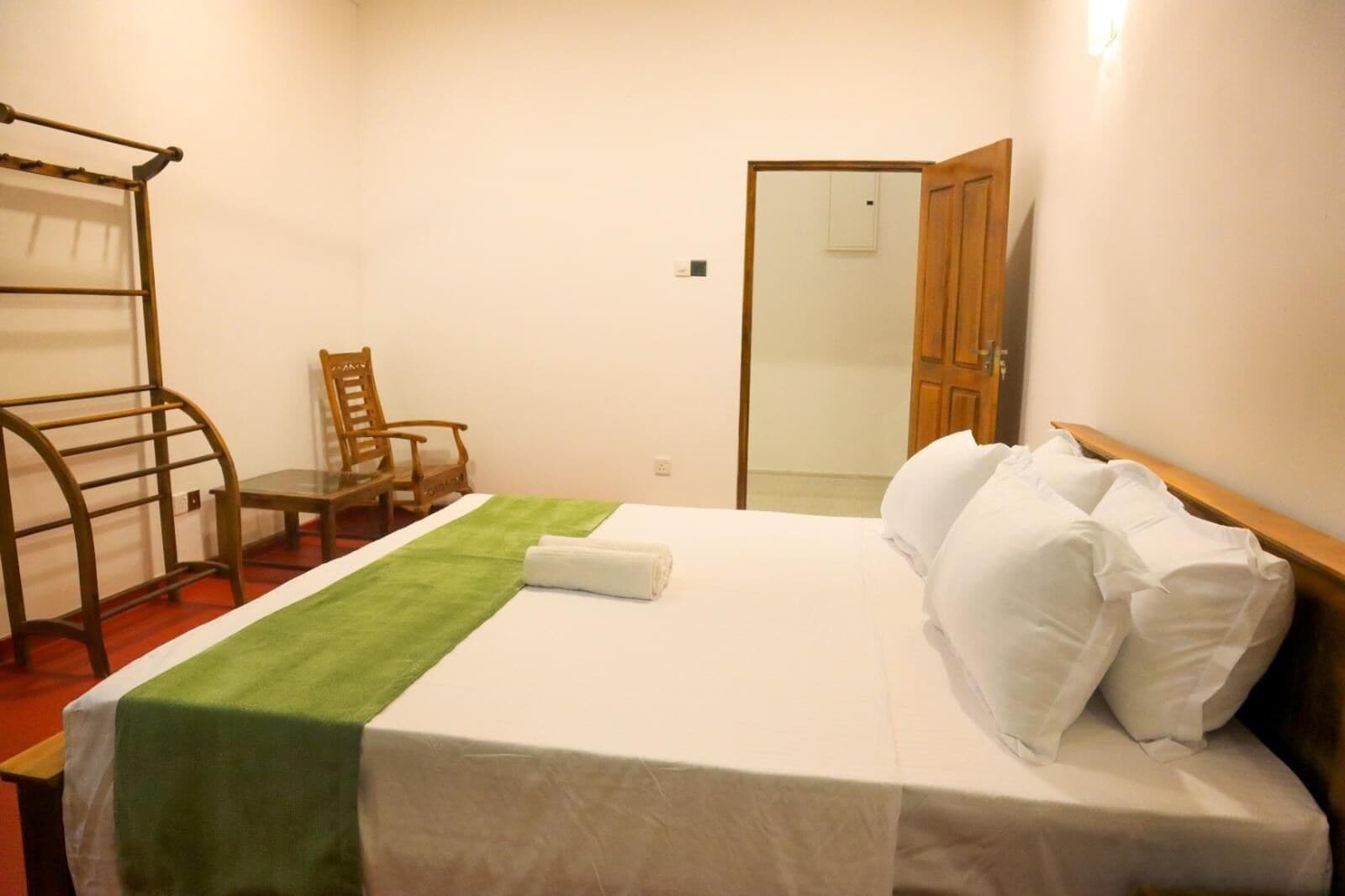 Una habitación de hotel con una cama, una silla, una mesita y un armario.