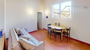Un salón acogedor con un sofá, una mesa de comedor con sillas, un ventanal con vistas y un equipo de aire acondicionado.