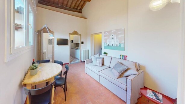Una habitación acogedora con una mesa de comedor, sillas, un sofá y una cocina al fondo.