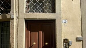 Un edificio de dos pisos con una puerta marrón y una ventana con barrotes.