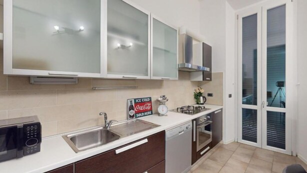 A modern kitchen with a microwave, sink, and cabinets. There is a sign indicating a sold item and a Coca-Cola sign. - Charlotte apartment wheels (Firenze)