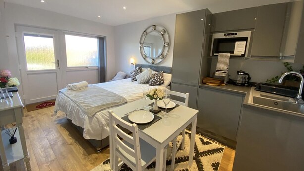 Ein kleines Hotelzimmer mit Bett, Nachttisch und einer kleinen Essecke mit Tisch und Stühlen.