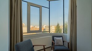 A room with two chairs, a table, and a view of buildings through a large window. - Charming 2BR Apartment - Steps to Romanian Athenaeum (Bucharest)
