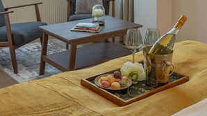 A hotel room with a large window, a wooden table with a tray of snacks, a bottle of champagne, and a view of the cityscape. - Charming 2BR Apartment - Steps to Romanian Athenaeum (Bucharest)