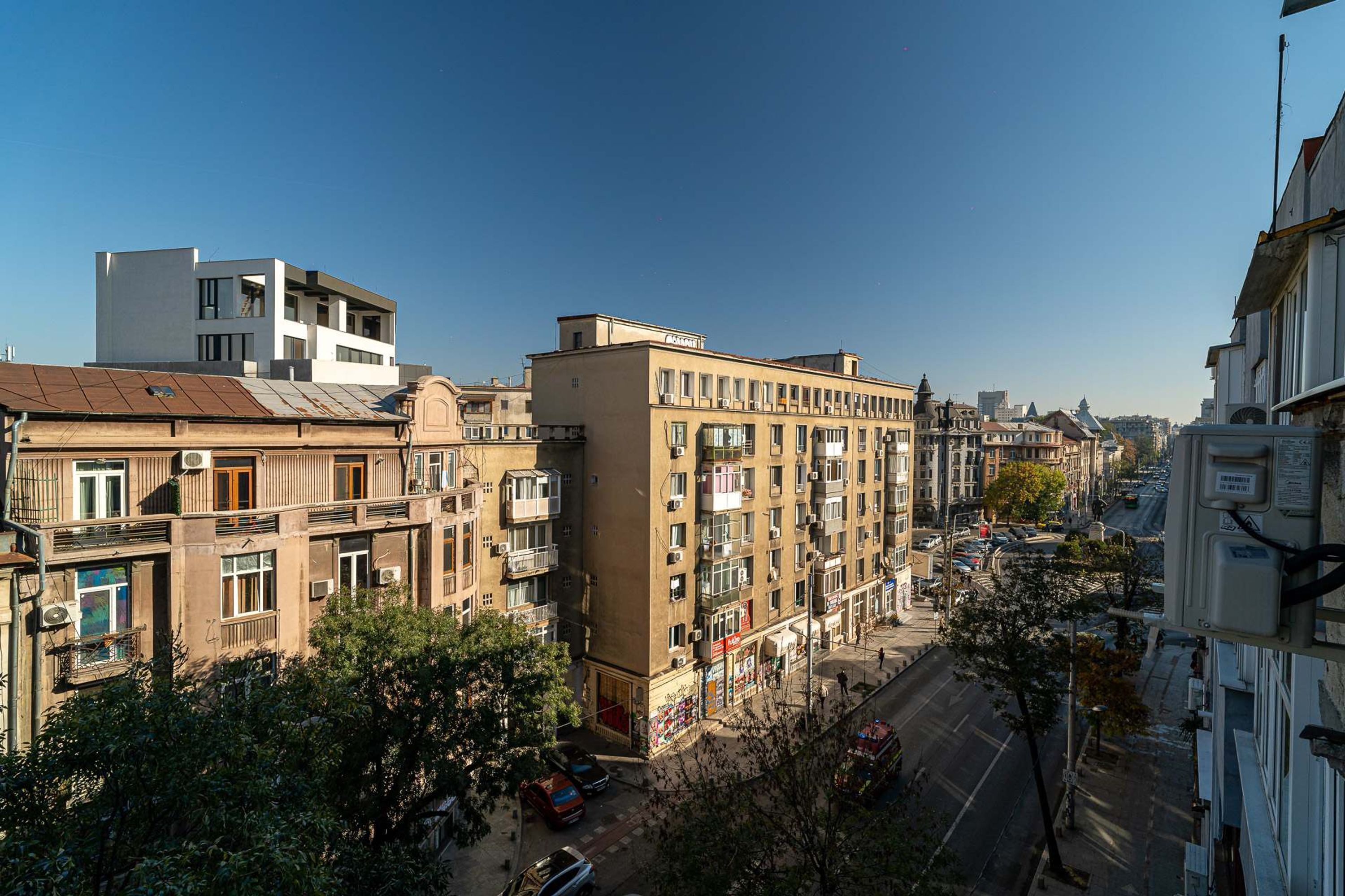 Ein mehrstöckiges Gebäude mit Balkonen, Blick auf eine Straße und geparkten Autos.
