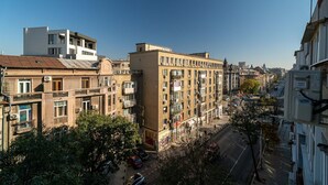 Un immeuble à plusieurs étages doté de balcons, donnant sur la rue, avec des voitures garées devant.