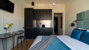 Une chambre d’hôtel moderne équipée d’un lit, d’un bureau, d’une kitchenette et d’une télévision.