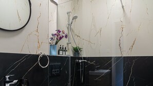 Une salle de bain moderne avec un pare-baignoire en marbre, un lavabo blanc, un meuble-vasque en bois, des toilettes et un espace douche.