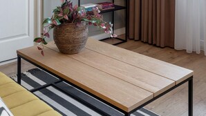 A living room with a wooden coffee table, a potted plant, a flat-screen TV, and a black TV stand.