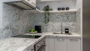 A modern kitchen with white cabinets, a marble backsplash, and a black countertop.