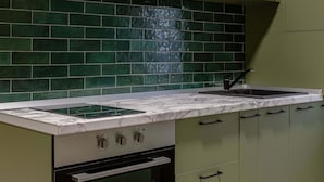 A kitchen with green cabinets, a black oven, and a tiled backsplash. - Serene 1BR Apartment in University Square (Bucharest)
