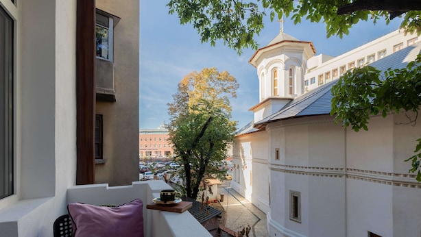 A balcony with a view of a tree and a building with a tower. - Serene 1BR Apartment in University Square (Bucharest)