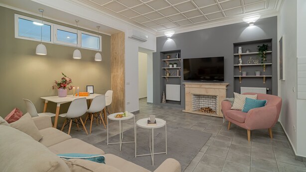 Una sala de estar moderna con un sofá, una mesa de comedor, sillas, una chimenea y un televisor.