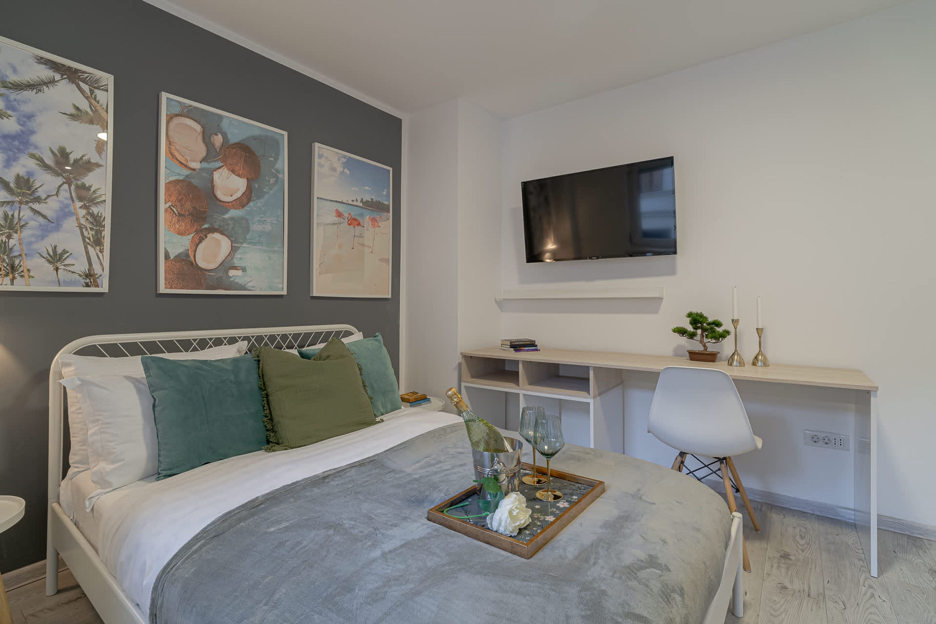 Een slaapkamer met een bed, een bureau, een televisie en kunst aan de muur.