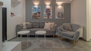 Una sala de estar moderna con un sofá gris, dos mesitas blancas y tres lámparas fijadas a la pared.