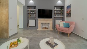 Una sala de estar con chimenea, televisor y sofá rosa.