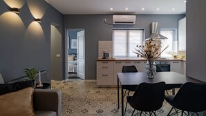A modern kitchen with a dining area, featuring a central island, pendant lighting, and a built-in stove. - Chic Black White 2BR Retreat on Dambovitei (Bucharest)