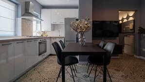 A modern kitchen with a dining area, featuring a large TV, a vase with flowers, and patterned flooring. - Chic Black White 2BR Retreat on Dambovitei (Bucharest)