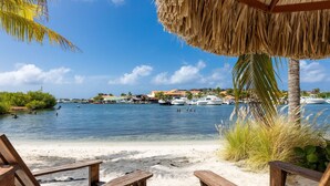 A beach with wooden chairs and a thatched roof structure. - Stylish Apartment With Pool Near Jan Thiel Beach (Jan Thiel)