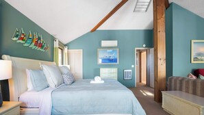 Une chambre à coucher avec un lit, une table de chevet, une commode et une fenêtre avec des rideaux.