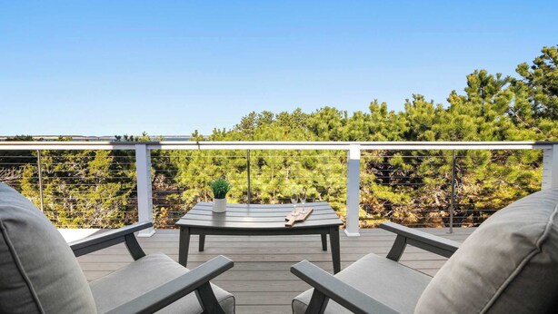 Une terrasse avec une table et des chaises, donnant sur une zone boisée.