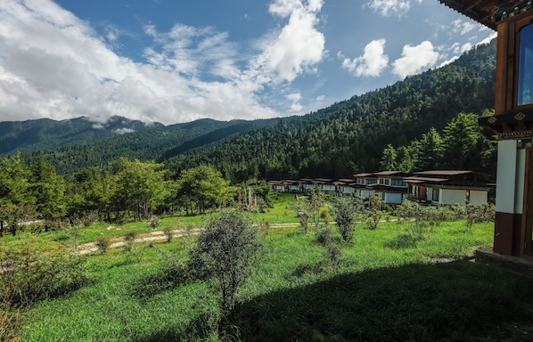 A mountainous landscape with a row of traditional-style buildings with flat roofs and a clear sky.