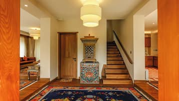 Un pasillo con escalera de madera, un pilar decorativo y una alfombra estampada.