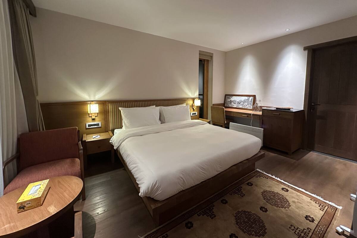 Une chambre d’hôtel avec un grand lit, des tables de chevet, un bureau, une chaise, une télévision et une armoire.