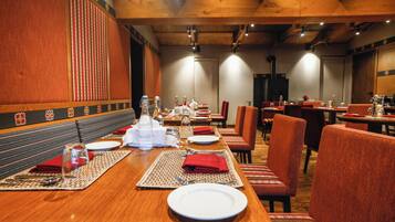 A restaurant with wooden tables, red upholstered chairs, and a patterned wall.
