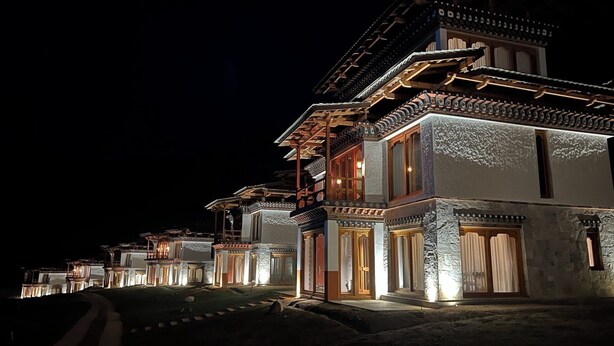 Un bâtiment traditionnel à plusieurs étages, doté d’une tour centrale imposante, qui est illuminée la nuit.