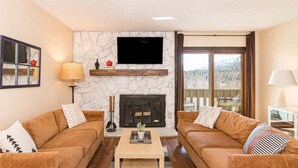A living room with two sofas, a fireplace, a television, and a view of the outdoors. - 2-bedroom 2 bath condo in Winter Park, magnificent views, hot tub, close to town (Winter Park)