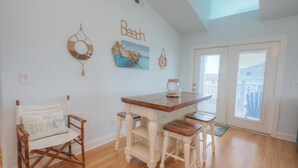 A dining area with a wooden table and bench, a chair with a cushion, and a wall with nautical-themed decorations. - Oceanview retreat in Oak Island with private pool, perfect for 11 guests. (Oak Island)