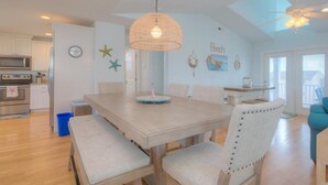 A spacious dining area with a large table, chairs, and a hanging light fixture. - Oceanview retreat in Oak Island with private pool, perfect for 11 guests. (Oak Island)