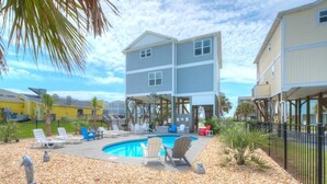 A two-story building with a swimming pool, outdoor seating, and a pebble ground cover. - Oceanview retreat in Oak Island with private pool, perfect for 11 guests. (Oak Island)