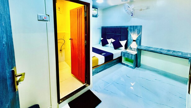 A hotel room with a bed, bedside table, lamp, and a door leading to another room. - Hotel BKC Fortune  (Mumbai)