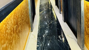 A hallway with marble flooring, black and gold walls, and doors with a sign indicating room number F8. - Hotel BKC Fortune  (Mumbai)