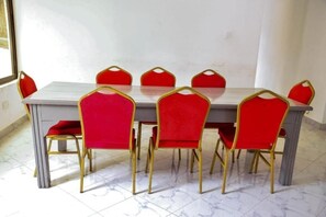 A dining table with six red chairs and gold legs.