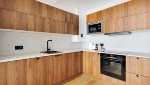 A modern kitchen with wooden cabinets, a stainless steel microwave, a built-in oven, and a black faucet.