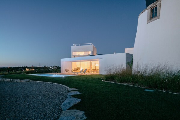 A modern house with a swimming pool, outdoor seating, and a well-maintained lawn. - Cabrita Moleiro - Design House (Lagoa)