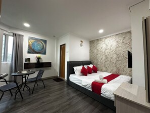 A modern hotel room with a bed, a desk, a chair, a small table, and a painting on the wall. - Malden Hotel (Kuala Lumpur)