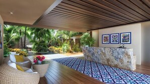 A modern lobby with a wooden ceiling, a reception desk, tropical plants, and a patterned floor. - Melittas Stylish 2Bed,2Bath-Condo Near Beach - 6 Guests (Playa del Carmen)