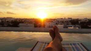 A sunset view from a poolside lounge with a cityscape in the background. - Melittas Stylish 2Bed,2Bath-Condo Near Beach - 6 Guests (Playa del Carmen)