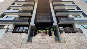 A multi-story building with a symmetrical facade, featuring balconies with metal railings and a central vertical element. - Melittas Stylish 2Bed,2Bath-Condo Near Beach - 6 Guests (Playa del Carmen)